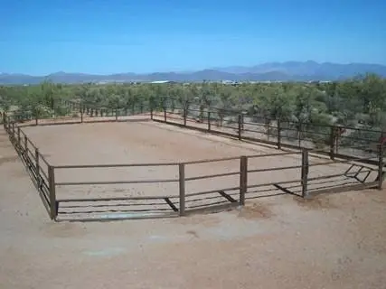 A large rectangular arena fenced in Corral Kraft steel panels, with desert and mountains beyond