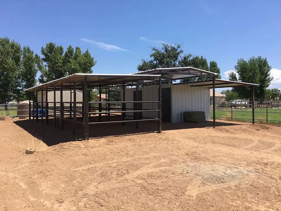 A four-stall Corral Kraft mare motel with an enclosed tack room at one end, standing on a green Arizona horse property