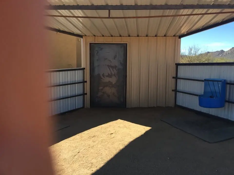 Inside a Corral Kraft covered stall, looking at the tack room door, the corrugated side walls and a corner waterer